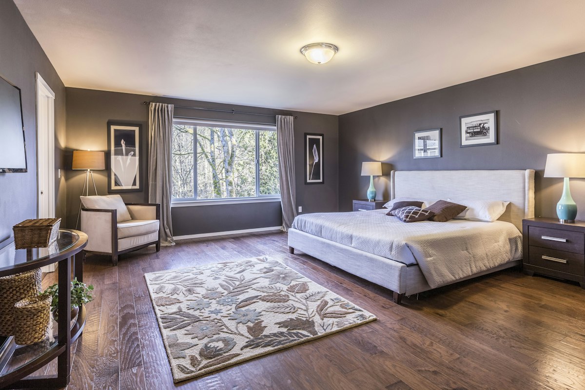 Clean hotel bedroom with upholstered headboard and natural light